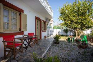 a patio with a table and chairs and a tree at FLOWERS STUDIOS in Skala