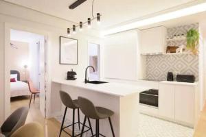 een keuken met een wastafel en 2 barkrukken bij GuestReady - Un Moderno Apartamento a un Paso de la Plaza Mayor in Madrid