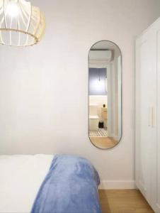 een slaapkamer met een spiegel en een blauw bed bij GuestReady - Un Moderno Apartamento a un Paso de la Plaza Mayor in Madrid