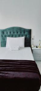a bedroom with a large white bed with a green headboard at CELEBRITY Hotel in Argostoli