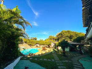 a resort with a swimming pool and a palm tree at Pousada Lua Nova Buzios in Búzios