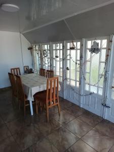 Un comedor con mesa y sillas y ventanas. en La Prietenicu, en Murighiol