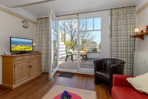 ein Wohnzimmer mit einem TV und einer Glasschiebetür in der Unterkunft Meeresblick Meeresblick 206 in Kühlungsborn