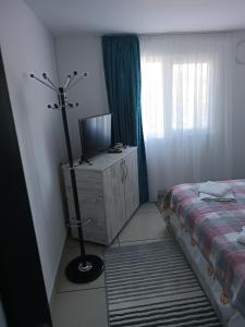 Un dormitorio con una cama y una cómoda con televisión. en La Prietenicu, en Murighiol