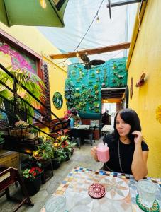 a woman sitting at a table with a pink drink at Central Boutique Hotel in Oranjestad
