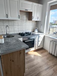 a kitchen with white cabinets and a sink and a window at Sky View in Marijampolė
