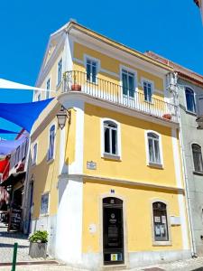 a yellow and white building with a balcony at The Corner House - Charming Rustic Home in the Heart of Monchique in Monchique