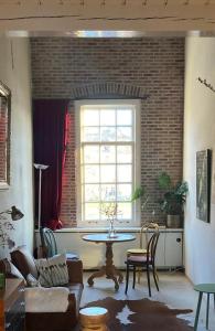 Una sala de estar con una mesa y una ventana. en Galerie Petit Delfshaven, en Róterdam