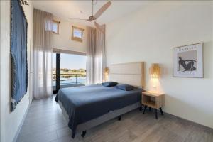 a bedroom with a blue bed and a balcony at Luxury Waterfront Retreat 4p - Comfort & Panoramisch Uitzicht - Villa 13 in Ouddorp