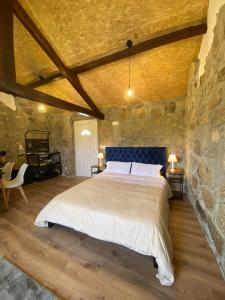 a bedroom with a large bed in a stone wall at Casa de Pedra em Vinha no Dão in Nelas