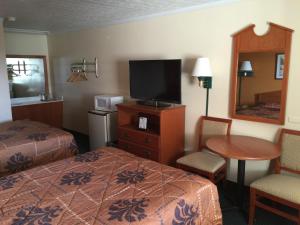 a hotel room with a bed and a tv and a table at Budget Inn - Saint Robert in Saint Robert