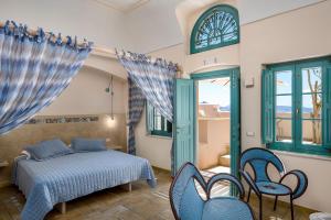a bedroom with a bed and chairs and a window at Passion Blue Villas in Oia +42 photos