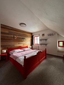 a bedroom with a red bed with a wooden wall at Žebřík postel Sušice in Sušice