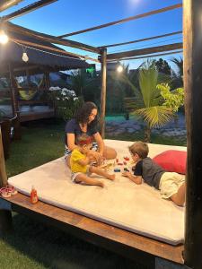 a woman and two children playing on a mattress at Pousada Solar Dos Carneiros in Praia dos Carneiros