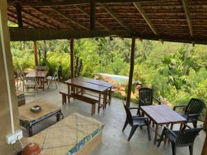 a patio with wooden tables and chairs and trees at Silver Hill Ecovillage in Kurunegala