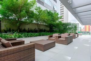 a patio with chairs and tables in a building at 7th Avenue - Apartamentos UROOMS in Curitiba