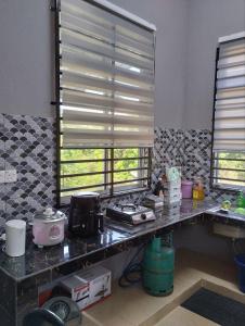 a kitchen with a counter and a window with blinds at SH Homestay in Kota Bharu