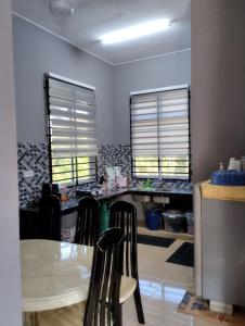 a dining room with a table and two windows at SH Homestay in Kota Bharu
