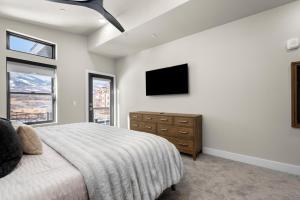 ein Schlafzimmer mit einem Bett und einem Fernseher an der Wand in der Unterkunft New East Deer Valley 1 min, B6302, Luxury 3Br Condo, Park City 10 min in Heber City