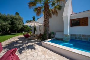 a villa with a palm tree and a swimming pool at Villa Giglio with Garden and Mini Pool by Rentbeat in Rosa Marina