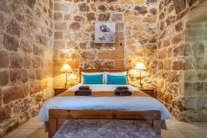 a bedroom with a bed in a stone wall at Sinjura Holiday Home in Xagħra +90 photos