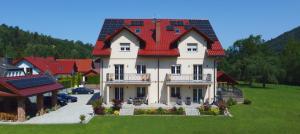 a house with a red roof with solar panels on it at Apartamenty Agroturystyczne Papiernia in Niedźwiedź
