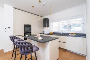 a kitchen with white cabinets and a island with two bar stools at Villa Sunset Dubrovnik in Dubrovnik