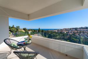 a balcony with two chairs and a view of a city at Villa Sunset Dubrovnik in Dubrovnik +37 photos