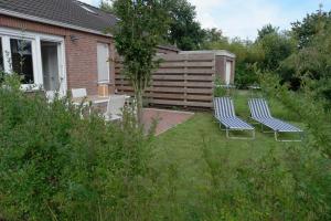 zwei Stühle im Gras im Garten in der Unterkunft Ferienhaus Ostfriesland im Teichweg in Berumbur