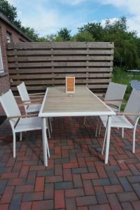 ein Picknicktisch und zwei Stühle auf einer gemauerten Terrasse in der Unterkunft Ferienhaus Ostfriesland im Teichweg in Berumbur + 14 Fotos