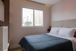 a bedroom with a large bed with a window at Studio prox shopping Curitiba Wifi, TV a Cabo e ar by UROOMS in Curitiba +44 photos
