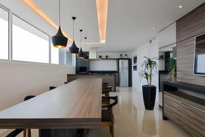 a kitchen with a large wooden table and chairs at Studio prox shopping Curitiba Wifi, TV a Cabo e ar by UROOMS in Curitiba