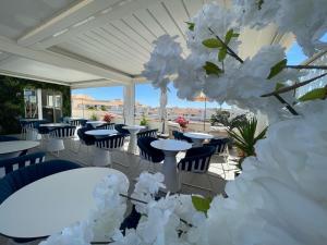 a row of tables and chairs on a patio with white flowers at Hôtel Eve Cap d'agde Village Naturiste in Cap d'Agde