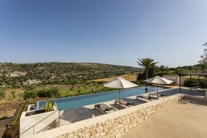 una piscina con sombrillas y sillas junto a en Corten House - IsulaTravel, en Módica