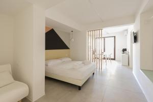 a white bedroom with a bed and a chair at Visitsicilia Vasile 9 in Castellammare del Golfo