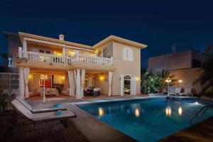 a villa with a swimming pool at night at Bayside Concha House - Beachfront Oasis with Heated Pool in Playa Honda