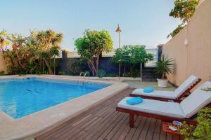 a swimming pool with two lounge chairs next to it at Bayside Concha House - Beachfront Oasis with Heated Pool in Playa Honda +44 photos