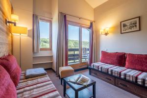 ein Wohnzimmer mit einer Couch und einem Fenster in der Unterkunft Résidence Pierre & Vacances Le Quartz in Belle Plagne