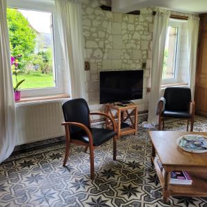 a living room with two chairs and a flat screen tv at Maison 1810 - Slow tourism in Fosseux