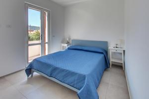 biała sypialnia z niebieskim łóżkiem i oknem w obiekcie Porto Ottiolu Resort w mieście Porto Ottiolu +37 zdjęć