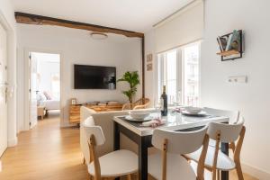 a dining room and living room with a table and chairs at La casa del Poeta in Santander