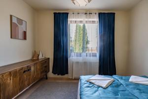 a bedroom with a bed and a window with blue curtains at Dom mazurski z basenem in Rydzewo
