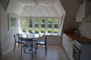 a kitchen with a table and chairs and windows at Ribe Dankirke Bed & Kitchen in Ribe