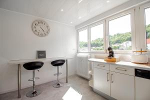 a kitchen with a clock on the wall and two stools at Sweet-Bright in Hayange +1 photo