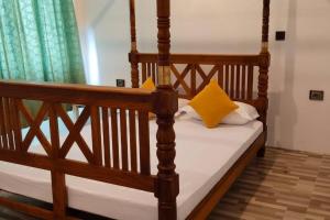 1 dormitorio con cama de madera y almohadas amarillas en Holiday Home Ragama, en Ragama