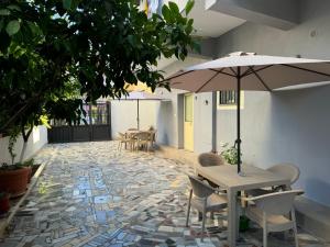 un patio avec tables, chaises et un parasol dans l'établissement Vivo Apartment, à Durrës