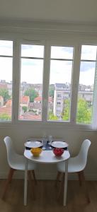 a white table with two chairs and three windows at Charmant Studio Cosy Confort in Alfortville