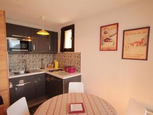 eine Küche mit einem Tisch und Stühlen sowie eine Küche mit einer Theke in der Unterkunft Charmant appart au 2e étage, 5 pers, balcon, WiFi, casier à skis, Les Saisies - FR-1-293-287 in Hauteluce + 8 Fotos