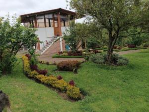 a house with a flower garden in front of it at Casa de Campo Quinta EL Paraíso in Ambato
