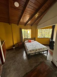 ein Schlafzimmer mit einem Bett in einem Zimmer mit gelben Wänden in der Unterkunft Bungalow de 02 pisos en casa de campo El Valle Inn in Cieneguilla